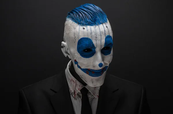 Terrible clown and Halloween theme: Crazy blue clown in black suit isolated on a dark background in the studio — 图库照片