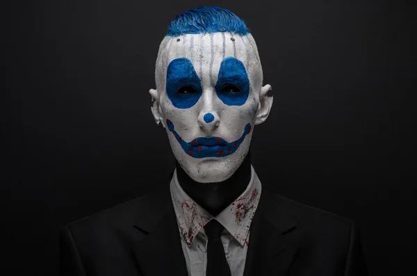 Terrible clown and Halloween theme: Crazy blue clown in black suit isolated on a dark background in the studio — Stok fotoğraf