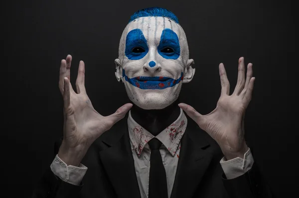 Schrecklicher Clown und Halloween-Thema: verrückter blauer Clown im schwarzen Anzug isoliert auf dunklem Hintergrund im Studio — Stockfoto