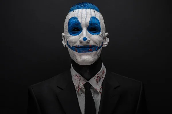 Schrecklicher Clown und Halloween-Thema: verrückter blauer Clown im schwarzen Anzug isoliert auf dunklem Hintergrund im Studio — Stockfoto