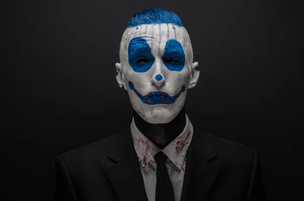 Schrecklicher Clown und Halloween-Thema: verrückter blauer Clown im schwarzen Anzug isoliert auf dunklem Hintergrund im Studio — Stockfoto