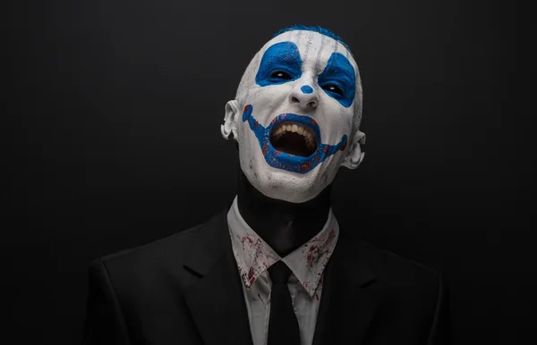 Terrible clown and Halloween theme: Crazy blue clown in black suit isolated on a dark background in the studio — 스톡 사진