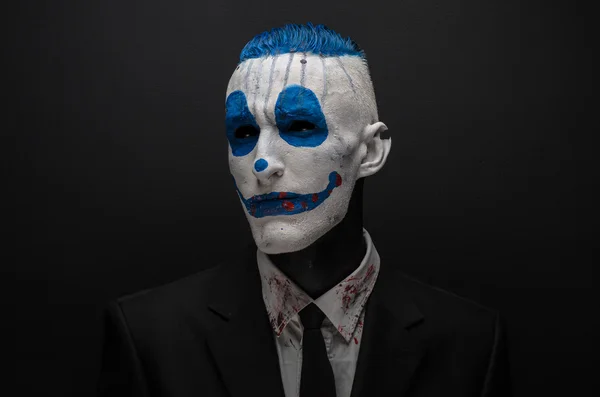 Terribile clown e tema Halloween: clown blu pazzo in abito nero isolato su uno sfondo scuro in studio — Foto Stock