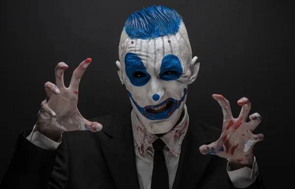 Terribile clown e tema Halloween: clown blu pazzo in abito nero isolato su uno sfondo scuro in studio — Foto Stock