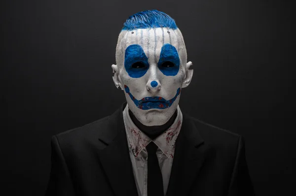 Terribile clown e tema Halloween: clown blu pazzo in abito nero isolato su uno sfondo scuro in studio — Foto Stock