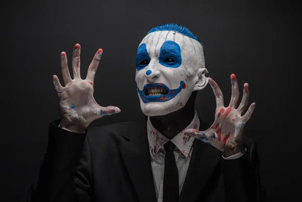 Terrible payaso y tema de Halloween: Payaso azul loco en traje negro aislado sobre un fondo oscuro en el estudio —  Fotos de Stock