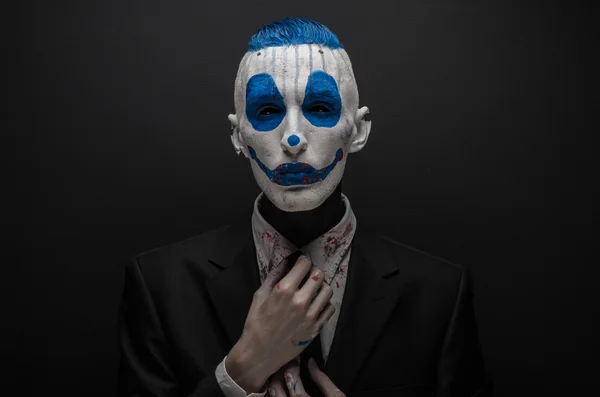 Terribile clown e tema Halloween: clown blu pazzo in abito nero isolato su uno sfondo scuro in studio — Foto Stock