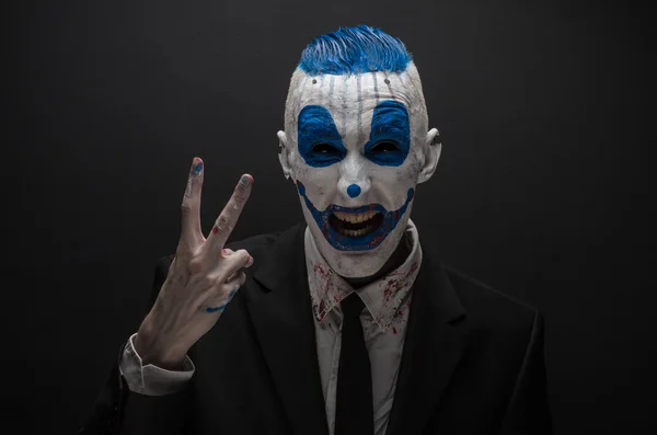 Terrible clown and Halloween theme: Crazy blue clown in black suit isolated on a dark background in the studio — Stockfoto