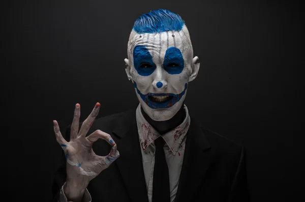 Terrible clown and Halloween theme: Crazy blue clown in black suit isolated on a dark background in the studio — ストック写真