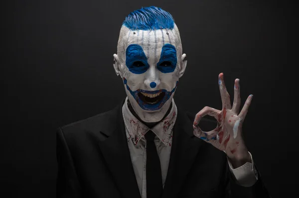 Terribile clown e tema Halloween: clown blu pazzo in abito nero isolato su uno sfondo scuro in studio — Foto Stock