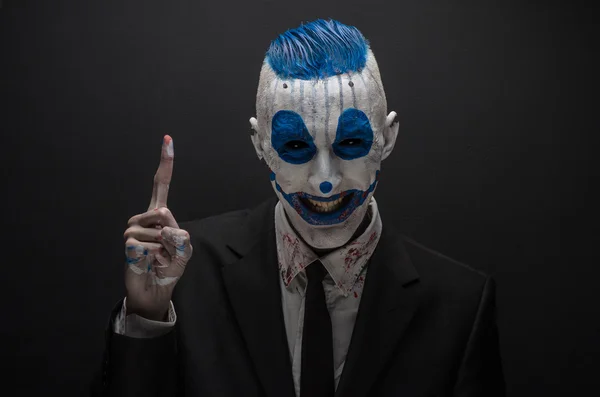 Schrecklicher Clown und Halloween-Thema: verrückter blauer Clown im schwarzen Anzug isoliert auf dunklem Hintergrund im Studio — Stockfoto