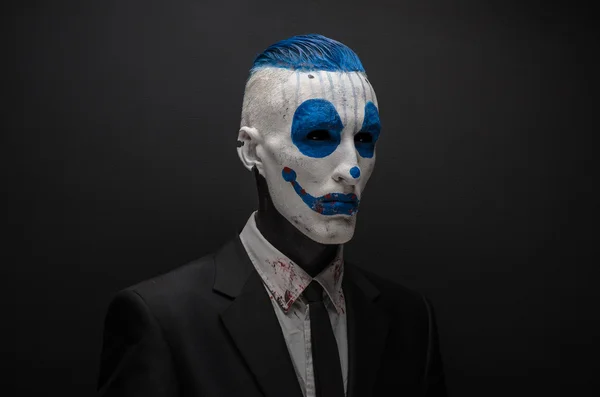 Terrible clown and Halloween theme: Crazy blue clown in black suit isolated on a dark background in the studio — Stockfoto