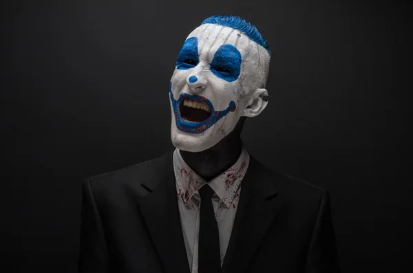 Terrible clown and Halloween theme: Crazy blue clown in black suit isolated on a dark background in the studio — 图库照片