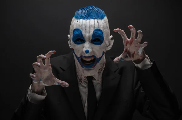 Terribile clown e tema Halloween: clown blu pazzo in abito nero isolato su uno sfondo scuro in studio — Foto Stock