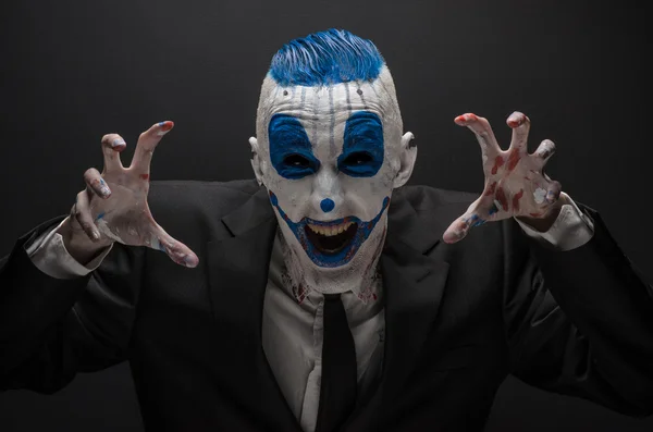 Terribile clown e tema Halloween: clown blu pazzo in abito nero isolato su uno sfondo scuro in studio — Foto Stock