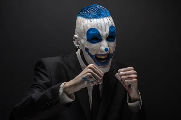 Terrible clown and Halloween theme: Crazy blue clown in black suit isolated on a dark background in the studio — Stock Fotó