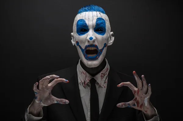 Terrible clown and Halloween theme: Crazy blue clown in black suit isolated on a dark background in the studio — Stok fotoğraf