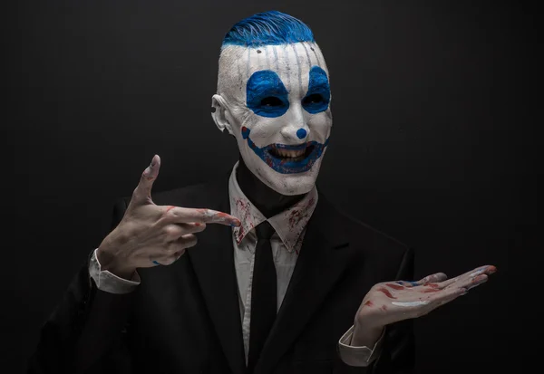 Terribile clown e tema Halloween: clown blu pazzo in abito nero isolato su uno sfondo scuro in studio — Foto Stock