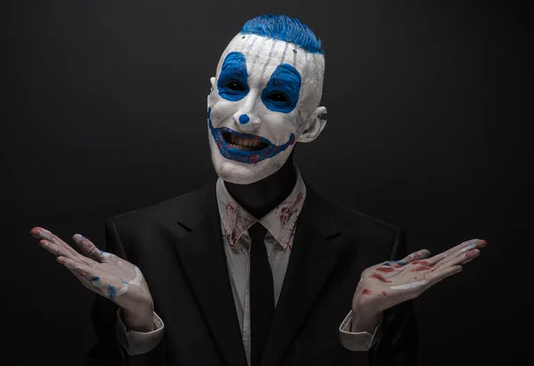 Terribile clown e tema Halloween: clown blu pazzo in abito nero isolato su uno sfondo scuro in studio — Foto Stock