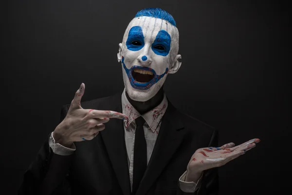 Terribile clown e tema Halloween: clown blu pazzo in abito nero isolato su uno sfondo scuro in studio — Foto Stock