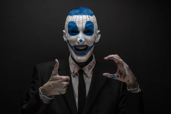 Terrible clown and Halloween theme: Crazy blue clown in black suit isolated on a dark background in the studio — 图库照片