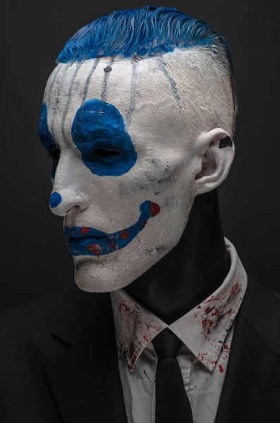 Schrecklicher Clown und Halloween-Thema: verrückter blauer Clown im schwarzen Anzug isoliert auf dunklem Hintergrund im Studio — Stockfoto