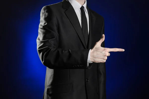 Negocio y presentación del tema: hombre en traje negro mostrando gestos de mano sobre fondo azul oscuro en estudio aislado —  Fotos de Stock