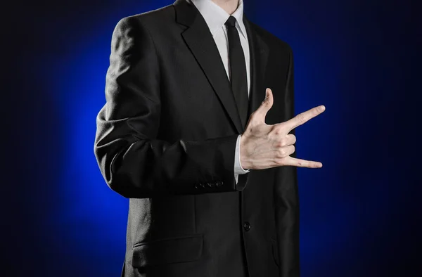 Бизнес и презентация темы: человек в черном костюме, показывающий жесты рук на темно-синем фоне в студии изолирован — стоковое фото