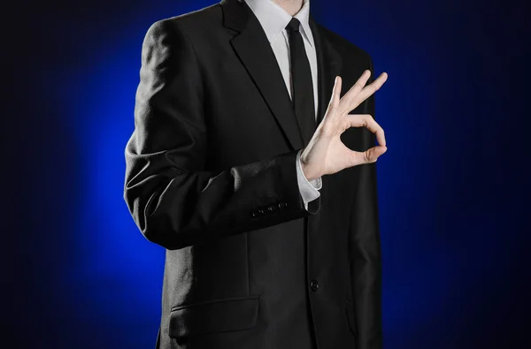 Negocio y presentación del tema: hombre en traje negro mostrando gestos de mano sobre fondo azul oscuro en estudio aislado —  Fotos de Stock