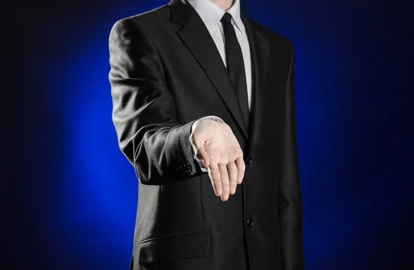 Business and the presentation of the theme: man in a black suit showing hand gestures on a dark blue background in studio isolated — Stockfoto