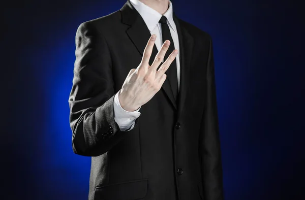 Business and the presentation of the theme: man in a black suit showing hand gestures on a dark blue background in studio isolated — Zdjęcie stockowe