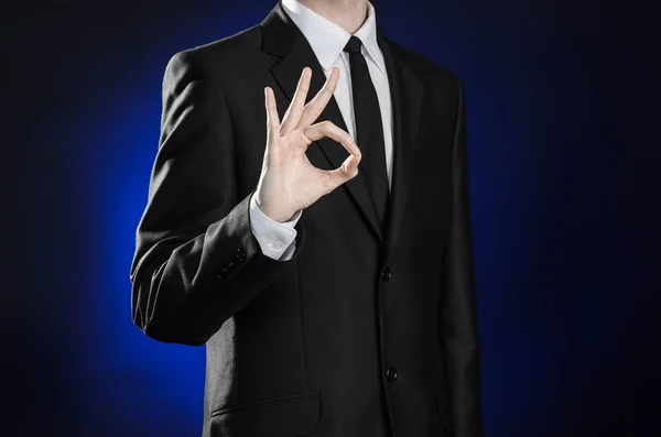 Business and the presentation of the theme: man in a black suit showing hand gestures on a dark blue background in studio isolated — Stock Photo, Image