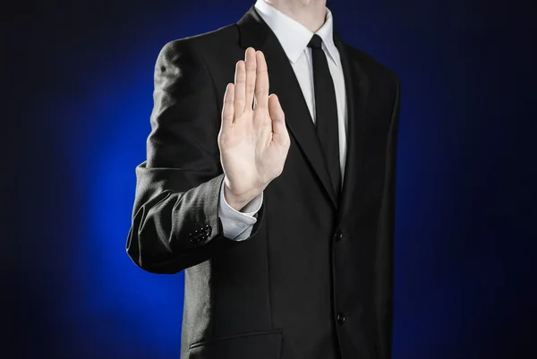 Business and the presentation of the theme: man in a black suit showing hand gestures on a dark blue background in studio isolated — Stockfoto