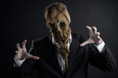 Fear and Halloween theme: a brutal killer in a mask on a dark background in the studio