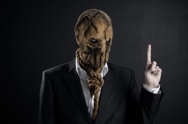 Fear and Halloween theme: a brutal killer in a mask on a dark background in the studio