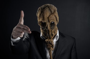 Fear and Halloween theme: a brutal killer in a mask on a dark background in the studio