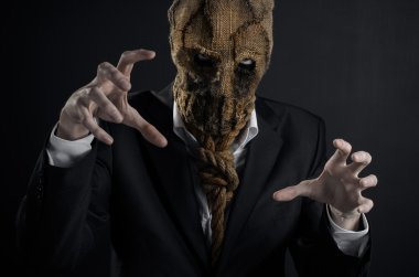 Fear and Halloween theme: a brutal killer in a mask on a dark background in the studio