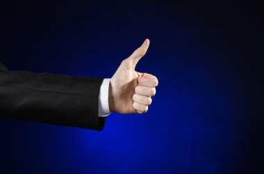 Businessman and gesture topic: a man in a black suit and white shirt showing hand gesture on an isolated dark blue background in studio