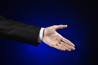 Businessman and gesture topic: a man in a black suit and white shirt showing hand gesture on an isolated dark blue background in studio