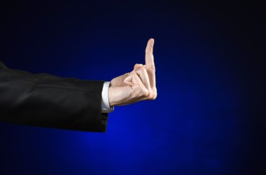 Businessman and gesture topic: a man in a black suit and white shirt showing hand gesture on an isolated dark blue background in studio
