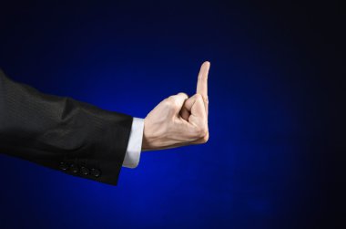 Businessman and gesture topic: a man in a black suit and white shirt showing hand gesture on an isolated dark blue background in studio