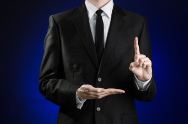Businessman and gesture topic: a man in a black suit and white shirt showing gestures with hands on a dark blue background in studio isolated