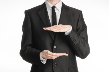 Businessman and gesture topic: a man in a black suit and tie holding two hands in front of him and shows the size on white isolated background in studio