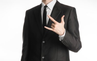 Businessman and gesture topic: a man in a black suit with a tie showing rock hand gesture on an isolated white background in studio