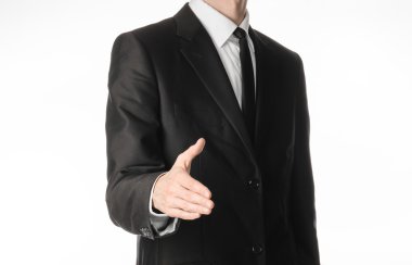 Businessman and gesture topic: a man in a black suit and tie holds out his hand to greet isolated on white background in studio