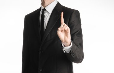 Businessman and gesture topic: a man in a black suit with a tie showing hand gesture finger up isolated on white background in studio