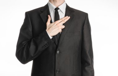 Businessman and gesture topic: a man in a black suit with a tie put his hand on his chest with a gesture in the form of a pistol isolated on white background in studio