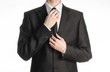 Businessman and gesture topic: a man in a black suit with a tie straightens his tie isolated on white background in studio