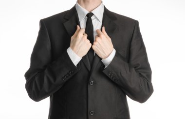 Businessman and gesture topic: a man in a black suit with a tie straightens his tie isolated on white background in studio