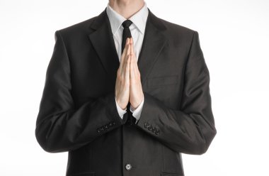Businessman and gesture topic: a man in a black suit with a tie folded his hands in front of him and praying, meditating businessman isolated on a white background in studio